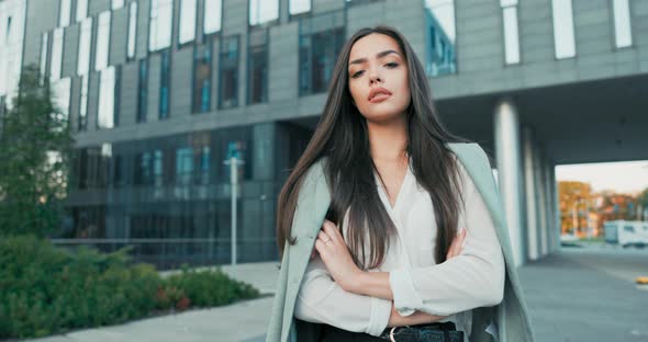 Smiling Girl with Brown Hair Stands of Corporate Building for Break Dressed in Smart Shirt and