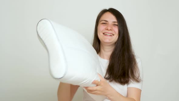 A Happy Woman Throws Up Her Beloved Orthopedic Pillow on a White Background