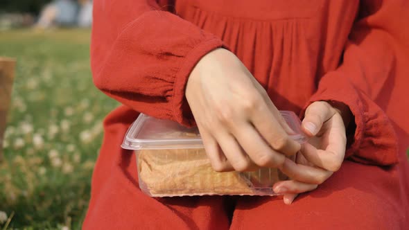 Woman in Dress Sits on Grass and Opens Plastic Container with Food, an Office Girl Took Takeaway in
