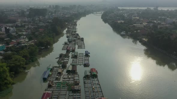 Floating fish farming community in Bien Hoa on the Dong Nai river, Vietnam on a sunny day. Drone fly