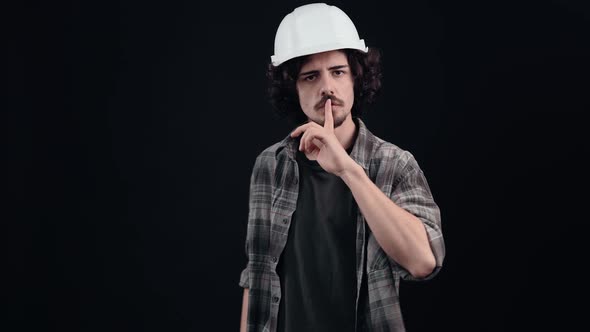 Young Worker with His Finger on His Lips Says to Shut Up Quietly