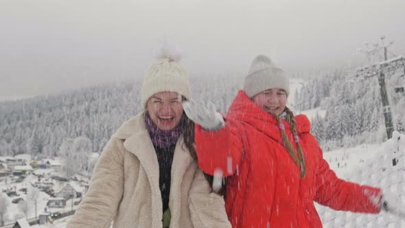 Young Woman Playing with Snow with Her Teenage Daughter