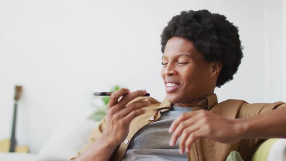 Happy african american man using smartphone at home