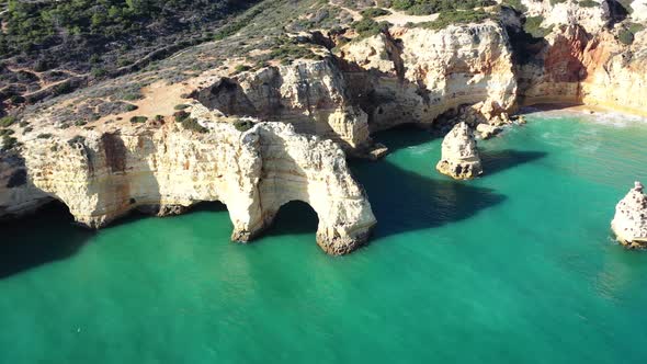 Rock eroded arch formations in Marinha Beach south of Portugal, Aerial pan right shot