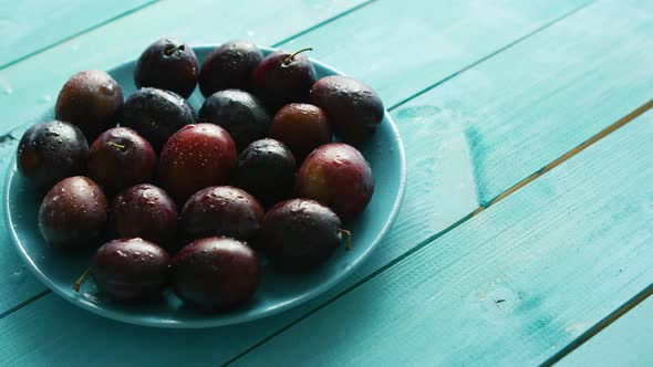 Plums on Blue Plate on Table