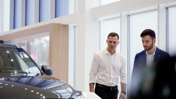 A Salesman Showing the New Car Model to a Client