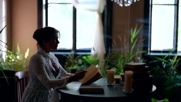 Beautiful Lady is Sitting in Vintage Room of Old Noble Estate Reading Old Love Novel Book