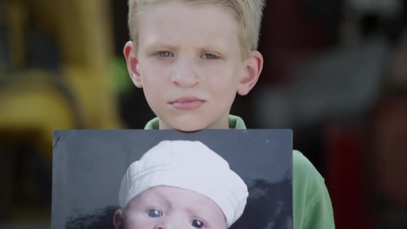 Slow motion from photo to boys face of him showing photo with cleft palate.