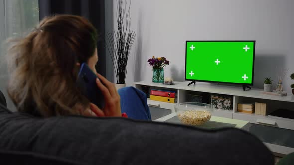Woman watching Tv Green Chroma Key Screen and talking on Phone.