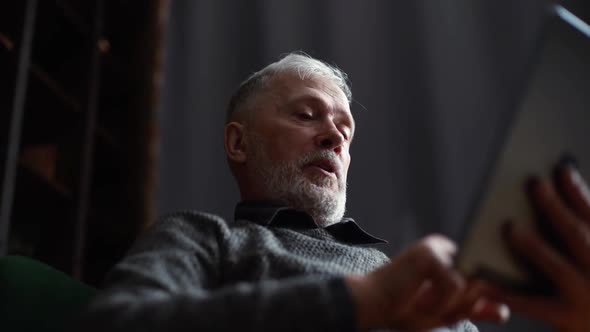 Closeup View From Below of Handsome Mature Adult Male Having Conversation By Digital Tablet