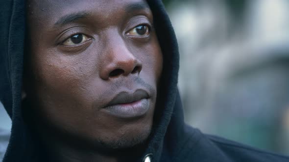 Young pensive hooded black african man staring into space