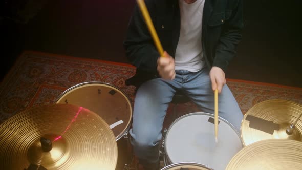 Drummer Playing the Drum Set in a Dark Room on a Black Background