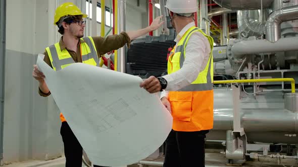 Engineer and Foreman are discussing the plant layout on the blueprint in the factory boiler room