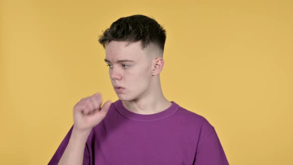 Sick Young Man Coughing on Yellow Background