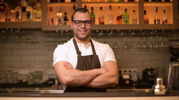 portrait of a confident smiling bartender at the bar in a restaurant