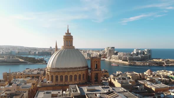 Carmelite Church dome with cityscape in background. Valletta, Malta. Aerial circling shot