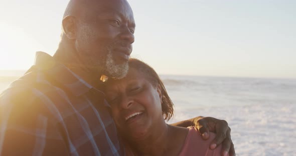 Smiling senior african american couple holding hands and dancing on sunny beach