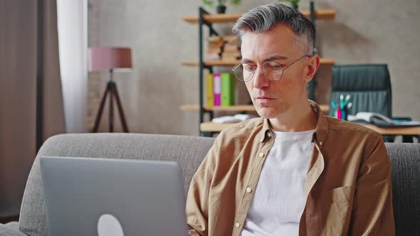 Close Up of Middle Aged Man Freelancer Working on Laptop Typing Article or Report on Computer and