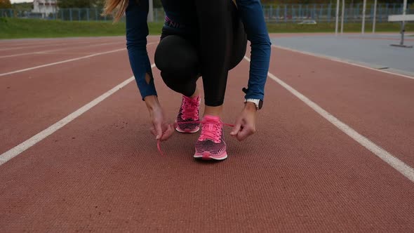 Sportswoman tying laces on sneakers on treadmill