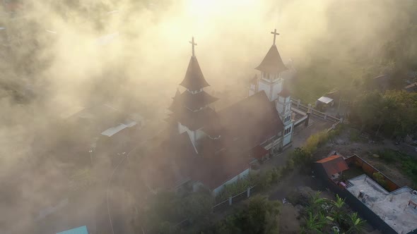 Aerial footage of a beautiful church in an Indonesian village on a misty day