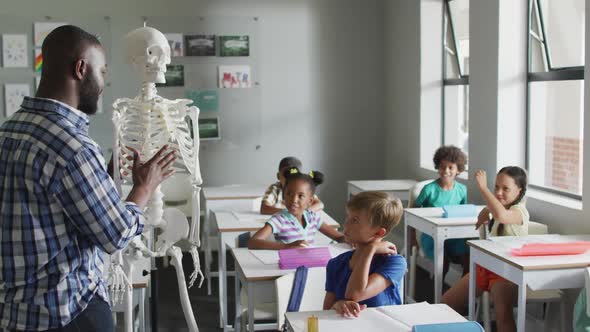 Video of happy african american teacher with class of diverse pupils during anatomy lesson