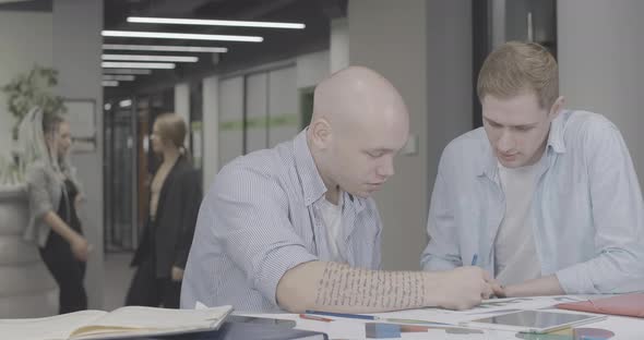 Portrait of Two Excited Male Colleagues Talking Shaking Hands in Office Hugging