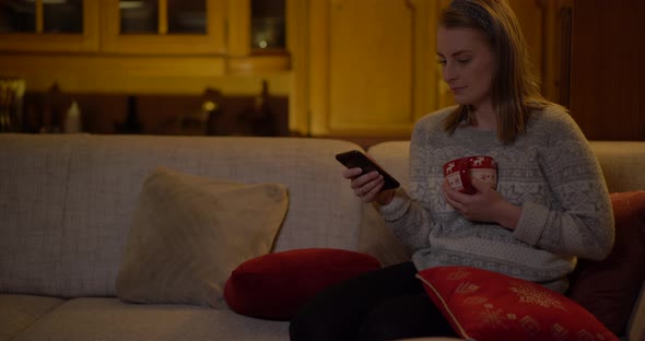 Young Woman Browsing Internet on Smartphone at Home