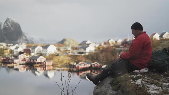 Hiker Resting On Rock By Reine Village