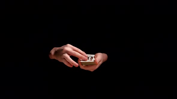 Magician Making Trick with Playing Cards on Black Background