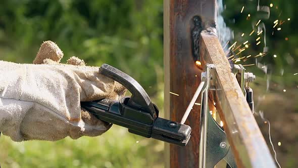 Close View Worker Connects Plank To Fence with Welding Tool