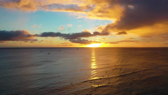 Colorful Sun Setting Over Group of Surfers and Boats Sailing At Dawn On Waikiki Beach in Honolulu Ha