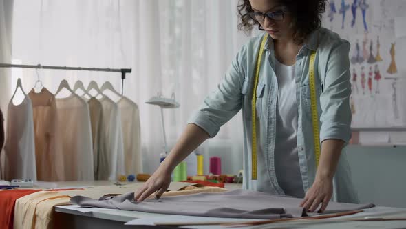 Dressmaker Unfolding Cloth on Work Table and Attaching Patterns, Fashion Design