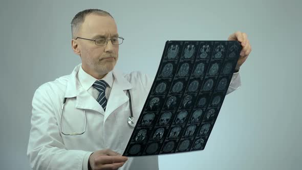 Unhappy Doctor Looking at MRI Brain Scan, Upset About Patient's Health Condition