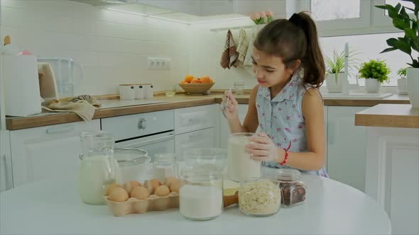 The Child Prepares the Dough in the Kitchen