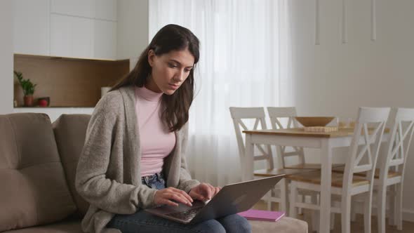 Young Woman Student is Typing an Essay Indoors in Living Room