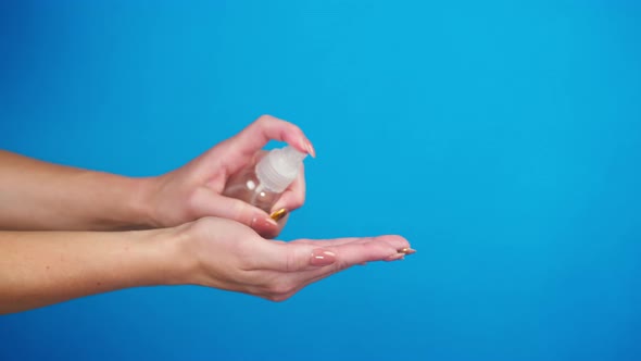 Female Hands Pushing Dispenser with Antiseptic on Blue Background