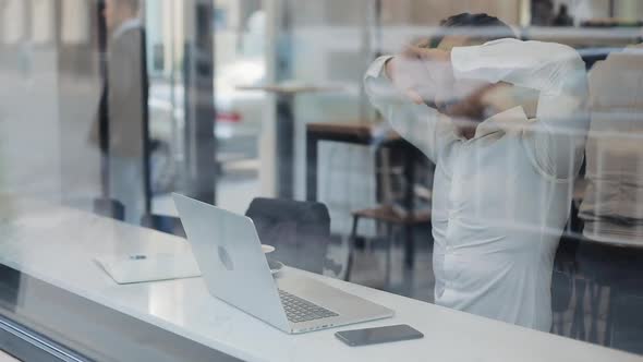 Tired Businessman Working on the Laptop in the Cozy Cafe and Yawning During Day Time