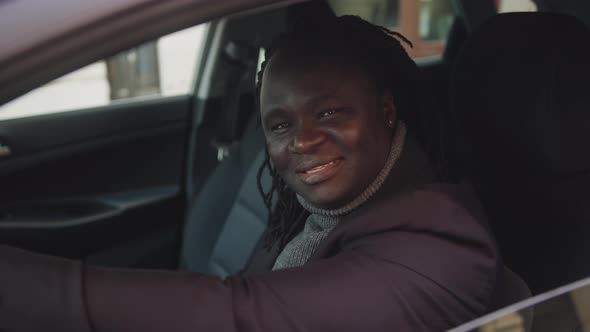 Happy African American Black Man Sitting on the Drivers Seat of His New Car and Smiling