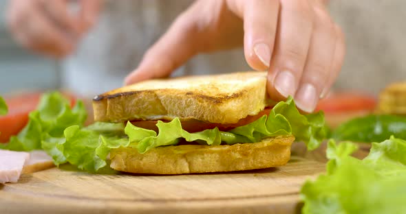 Female Chef in the Kitchen of the House Collects a Sandwich