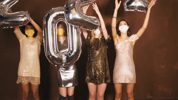 Four young international beautiful brunette women in trendy summer shiny dresses holding balloons