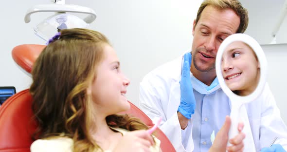 Dentist teaching girl to a brush teeth