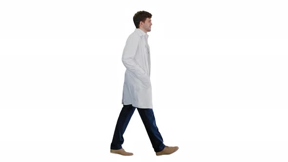 Male Doctor in White Coat Walking with Hands in Pockets Looking Straight Ahead on White Background