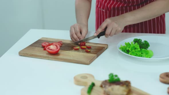 Close up hands of woman chop and slice tomatoes in to small pieces then put for decorating on plate