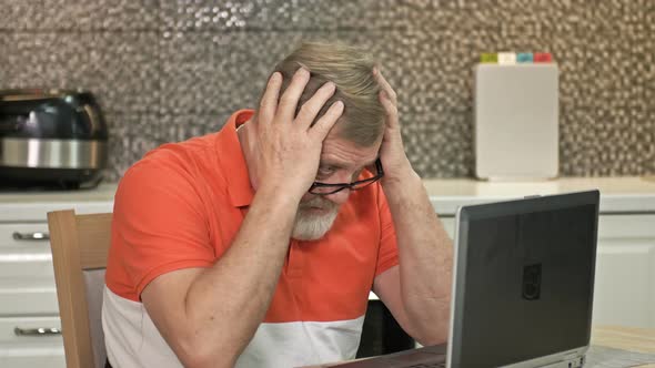 An Elderly Man Sits in Front of a Laptop