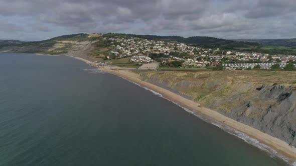 Aerial tracking from sea in towards the village of Charmouth. Amazing Jurassic coast cliffs surround