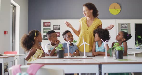 Video of happy caucasian female teacher and african american pupils studying ecology in classroom