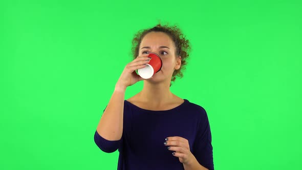 Portrait of Curly Woman Drinking Unpalatable Coffee and Is Disgusted . Green Screen