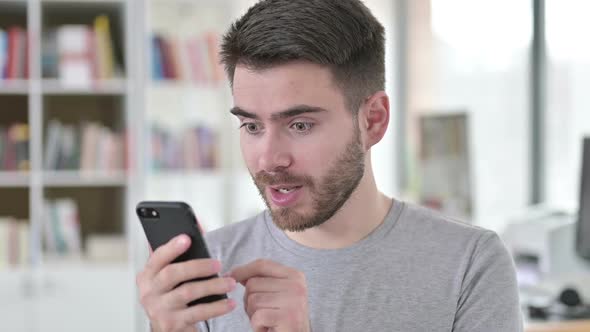 Portrait of Young Man Celebrating Success on Smartphone