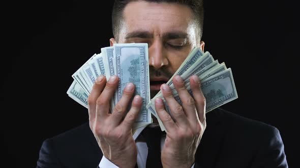 Greedy Business Man Stroking Face With Dollars Banknotes, Enjoying Wealth