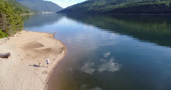 Woman with her pet dog walking near river coast on a sunny day 4k